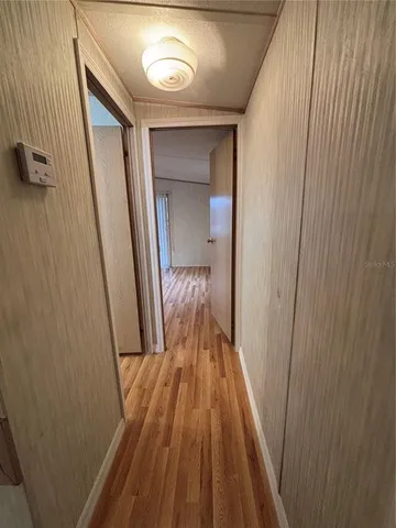 a view of a hallway with wooden floor and a bathroom