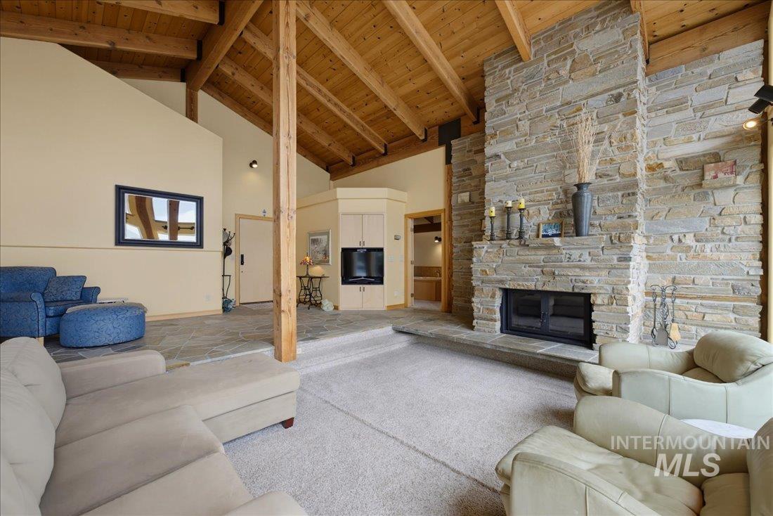 3800 Warren Wagon Road McCall, ID 83638 - Photo 11 of 50 Vaulted wood-paneled ceilings with exposed beams, a floor-to-ceiling stone fireplace, and multi-level flooring
