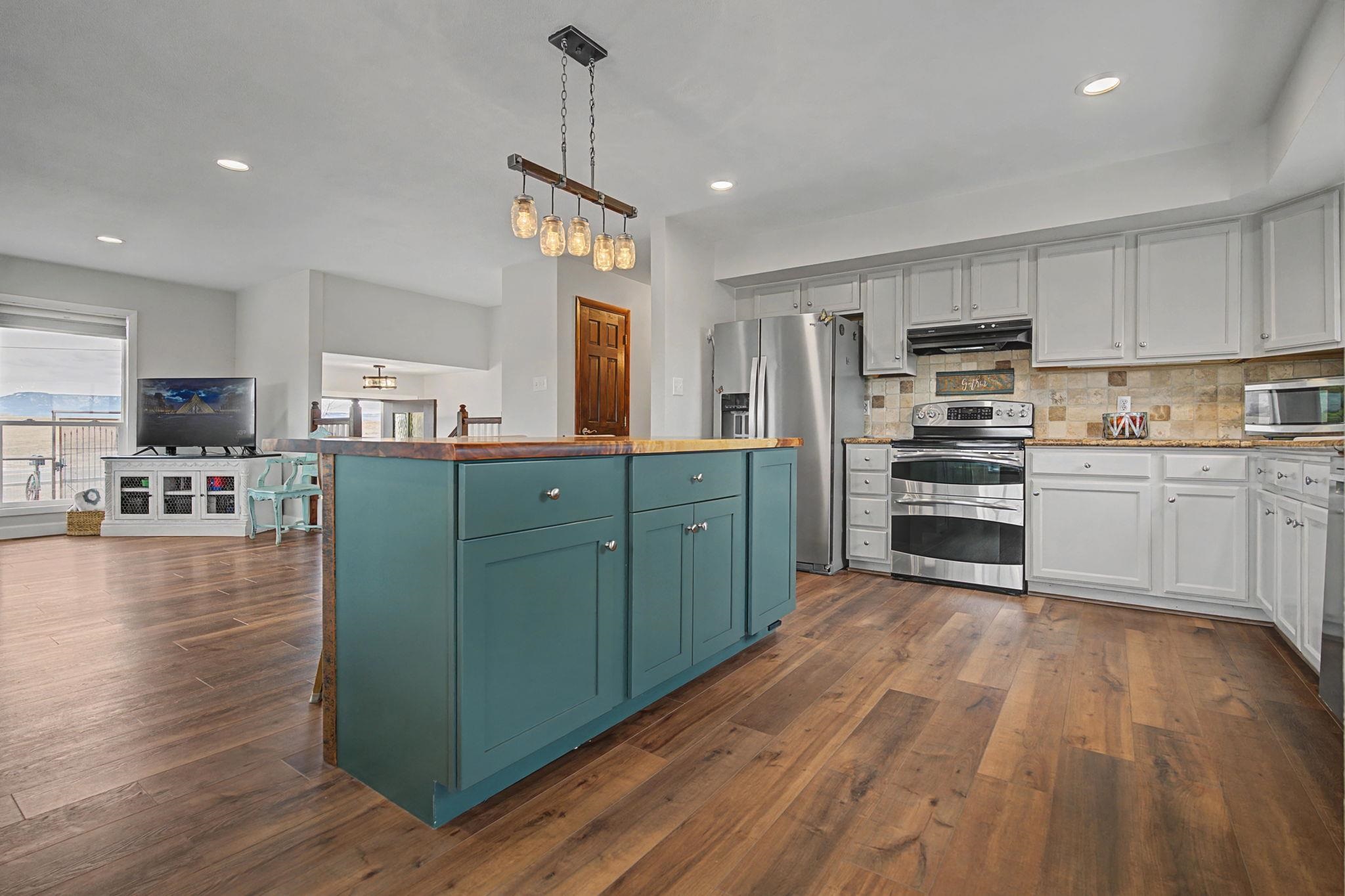 847 26 Road Grand Junction, CO 81505 - Photo 9 of 41 a kitchen with stainless steel appliances kitchen island granite countertop a refrigerator a stove top oven a sink dishwasher and white cabinets with wooden floor
