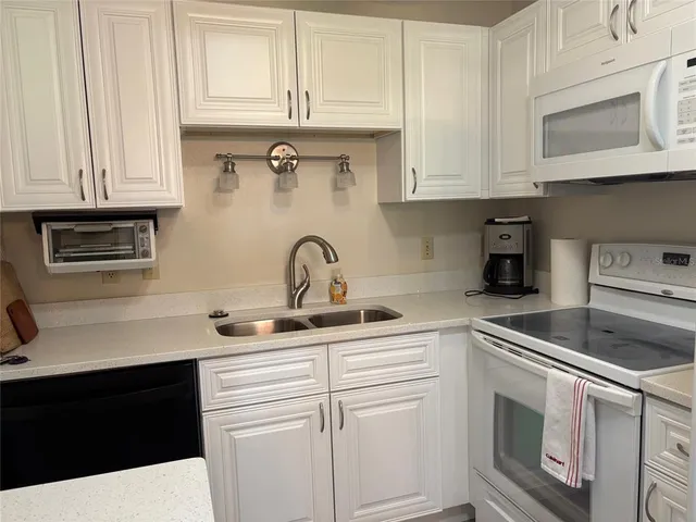 a kitchen with white cabinets and white appliances
