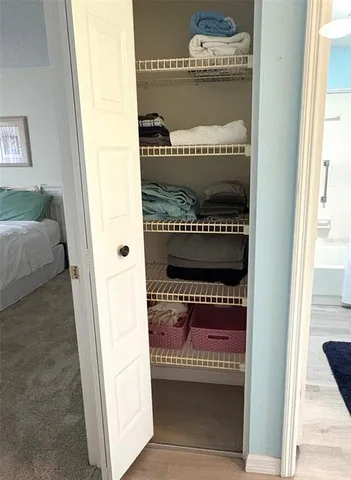 a view of a hallway with wooden floor and a bathroom