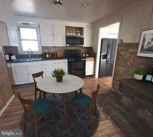 a kitchen with stainless steel appliances a dining table chairs refrigerator and microwave