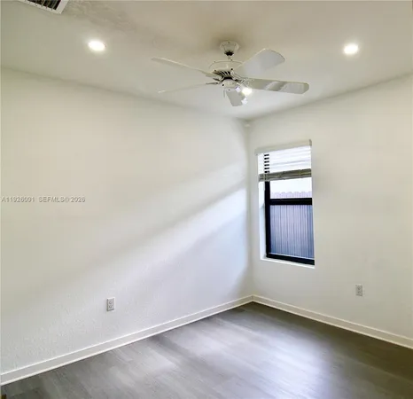 an empty room with wooden floor chandelier fan and windows