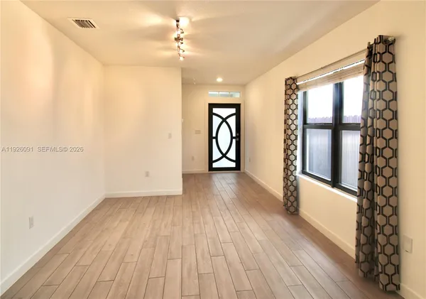 a view of an empty room with window and wooden floor