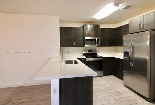 a kitchen with kitchen island a counter top space cabinets and stainless steel appliances