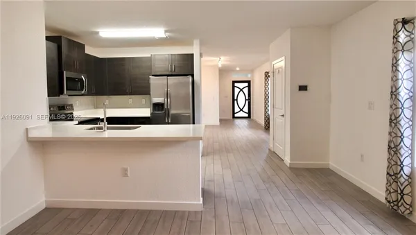 a kitchen with a sink a refrigerator and chairs