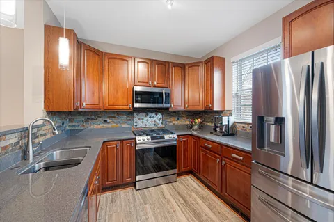 a kitchen with stainless steel appliances granite countertop a sink dishwasher stove refrigerator and cabinets