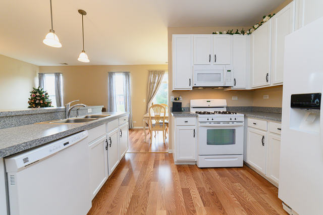 604 Springbrook Trail North Oswego, IL 60543 - Photo 5 of 22 a kitchen with granite countertop white cabinets and white appliances