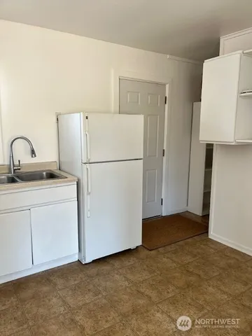 a view of a kitchen with refrigerator and a sink
