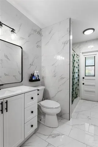 a bathroom with a granite countertop sink a toilet and shower