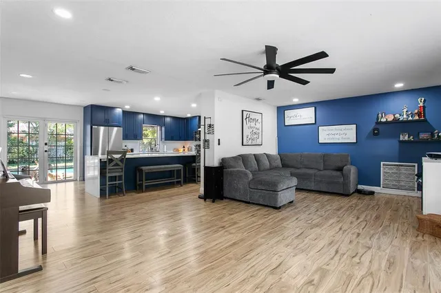 a living room with furniture kitchen view and a wooden floor