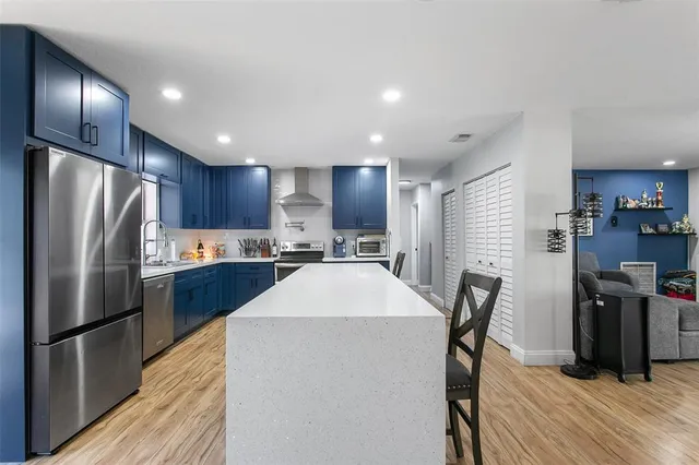 a kitchen with stainless steel appliances a refrigerator a stove a sink dishwasher with a dining table and chairs