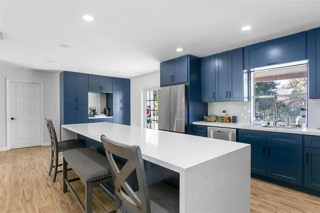 a kitchen with stainless steel appliances a table chairs refrigerator and wooden cabinets