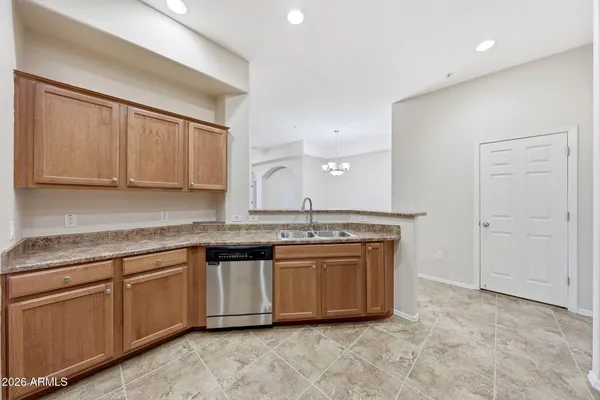 a view of a kitchen with granite countertop a sink and dishwasher a stove with wooden cabinets