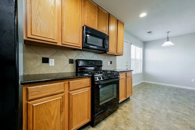 a kitchen with stainless steel appliances granite countertop a stove a sink and a refrigerator