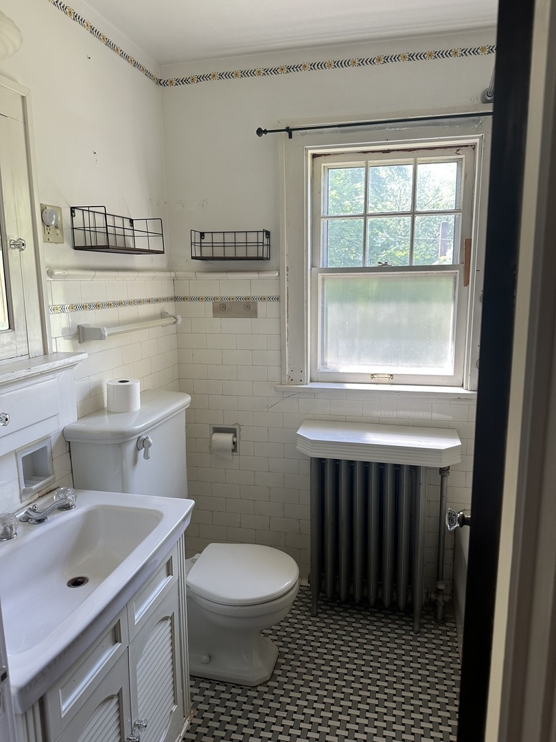1418 North Sheridan Road Peoria, IL 61606 - Photo 28 of 34 a bathroom with a toilet a sink a window and mirror