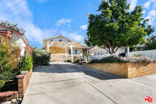 a front view of a house with a yard and potted plants