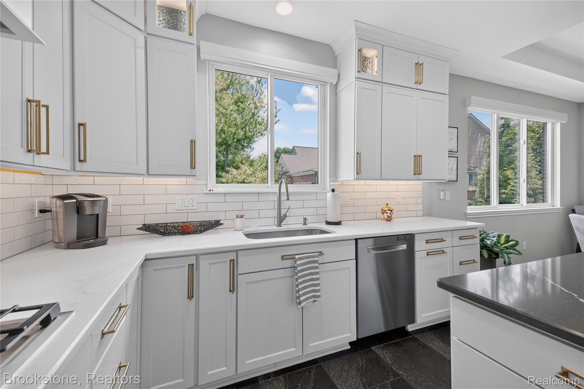 2167 Sanctuary Court Rochester, MI 48309 - Photo 6 of 68 Contemporary kitchen featuring white shaker cabinetry with gold-toned hardware, white subway tile backsplash, and light-toned countertops