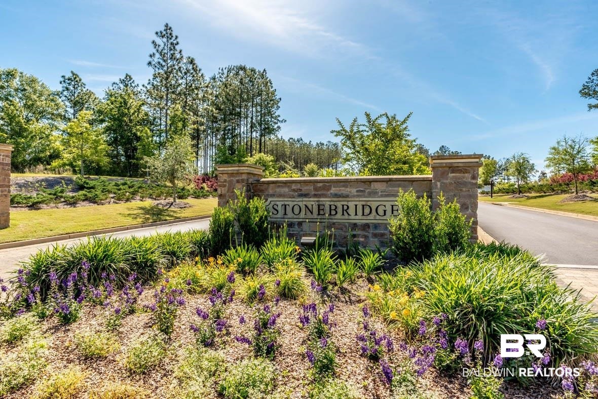 32125 Lyon Road Daphne, AL 36527 - Photo 69 of 70 Stone bridge community entrance featuring a stone monument sign, mature trees, manicured landscaping, and purple flowering plants