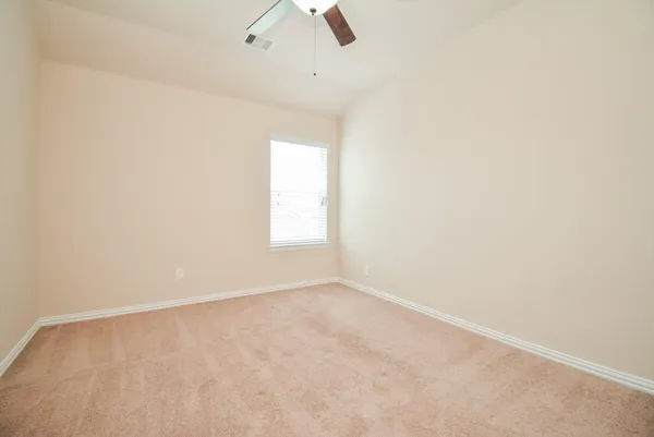 an empty room with ceiling fan and window