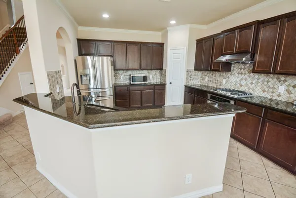 a kitchen with stainless steel appliances granite countertop a sink a stove and a refrigerator