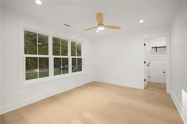 an empty room with a ceiling fan and windows