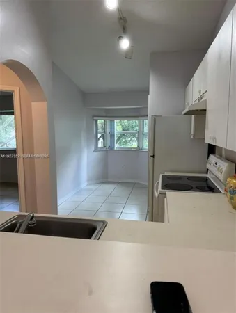 a view of kitchen with sink and refrigerator