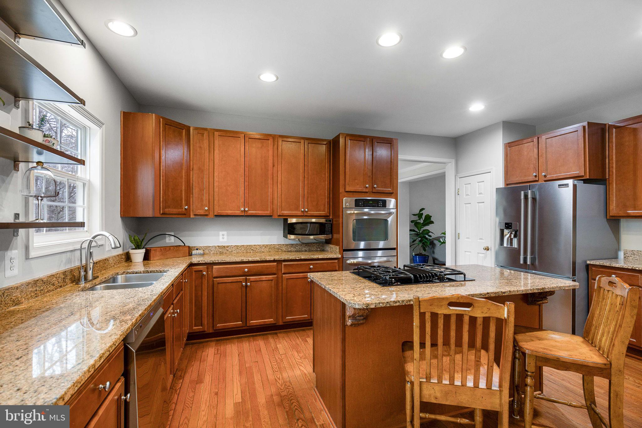 a kitchen with stainless steel appliances granite countertop sink stove refrigerator and cabinets