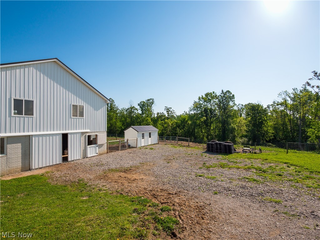 4182 Tooms Road Cumberland, OH 43732 - Photo 25 of 37 Two-story barn with white vertical siding and foundation, featuring multiple windows and a sliding barn door
