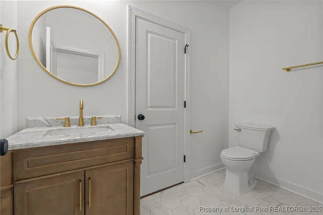 a bathroom with a granite countertop toilet a sink and a mirror