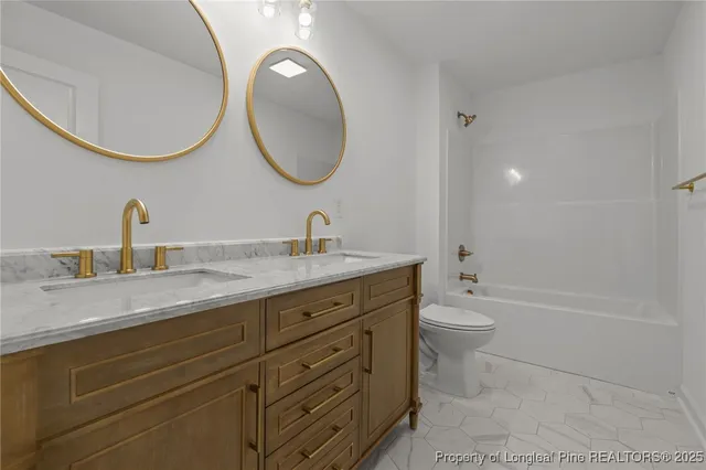 a bathroom with a granite countertop toilet a sink and a mirror