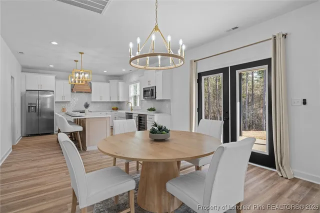 a kitchen with stainless steel appliances granite countertop a sink a stove a refrigerator cabinets and a dining table