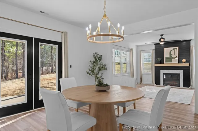 a kitchen with stainless steel appliances kitchen island granite countertop a refrigerator a sink dishwasher a stove a dining table and chairs with wooden floor