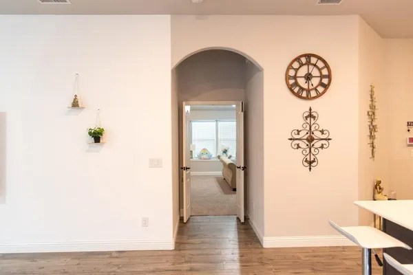 a view of a hallway with wooden floor and a dining table