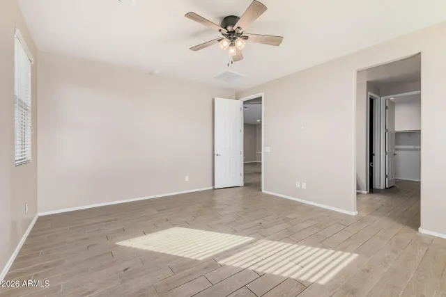 a view of a big room with wooden floor and a chandelier fan