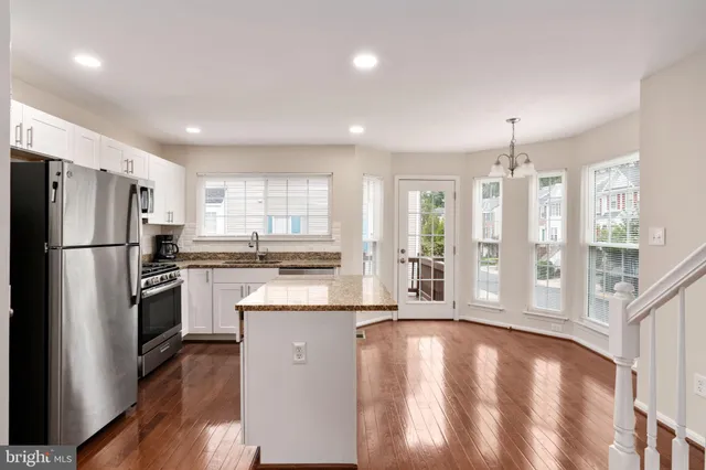 a kitchen with stainless steel appliances granite countertop a refrigerator a sink dishwasher a stove and a refrigerator with wooden floor