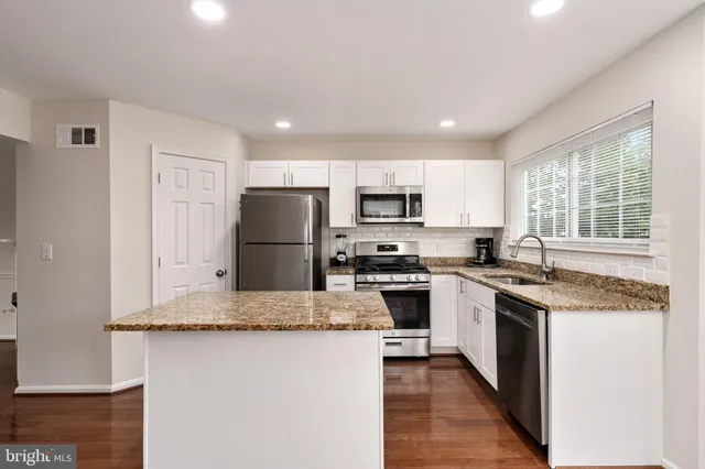 a kitchen with granite countertop stainless steel appliances a refrigerator sink stove microwave and cabinets