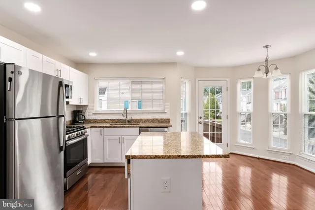 a kitchen with granite countertop a refrigerator a sink a stove and oven