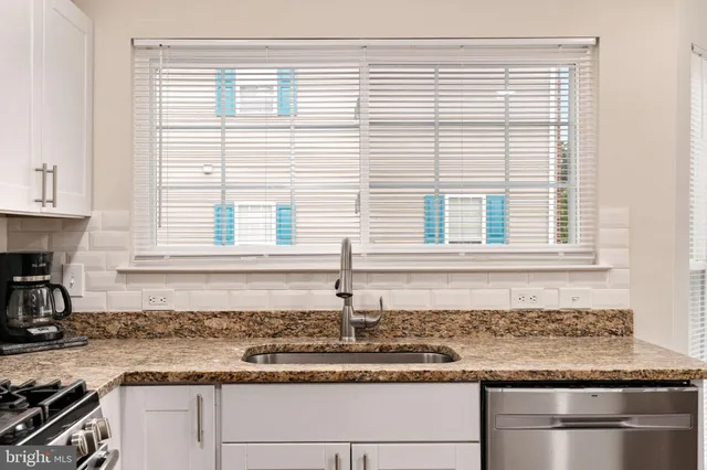 a kitchen with granite countertop white cabinets and a window