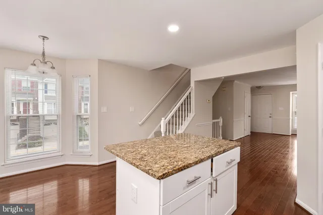 a kitchen with kitchen island granite countertop a stove and a wooden floors