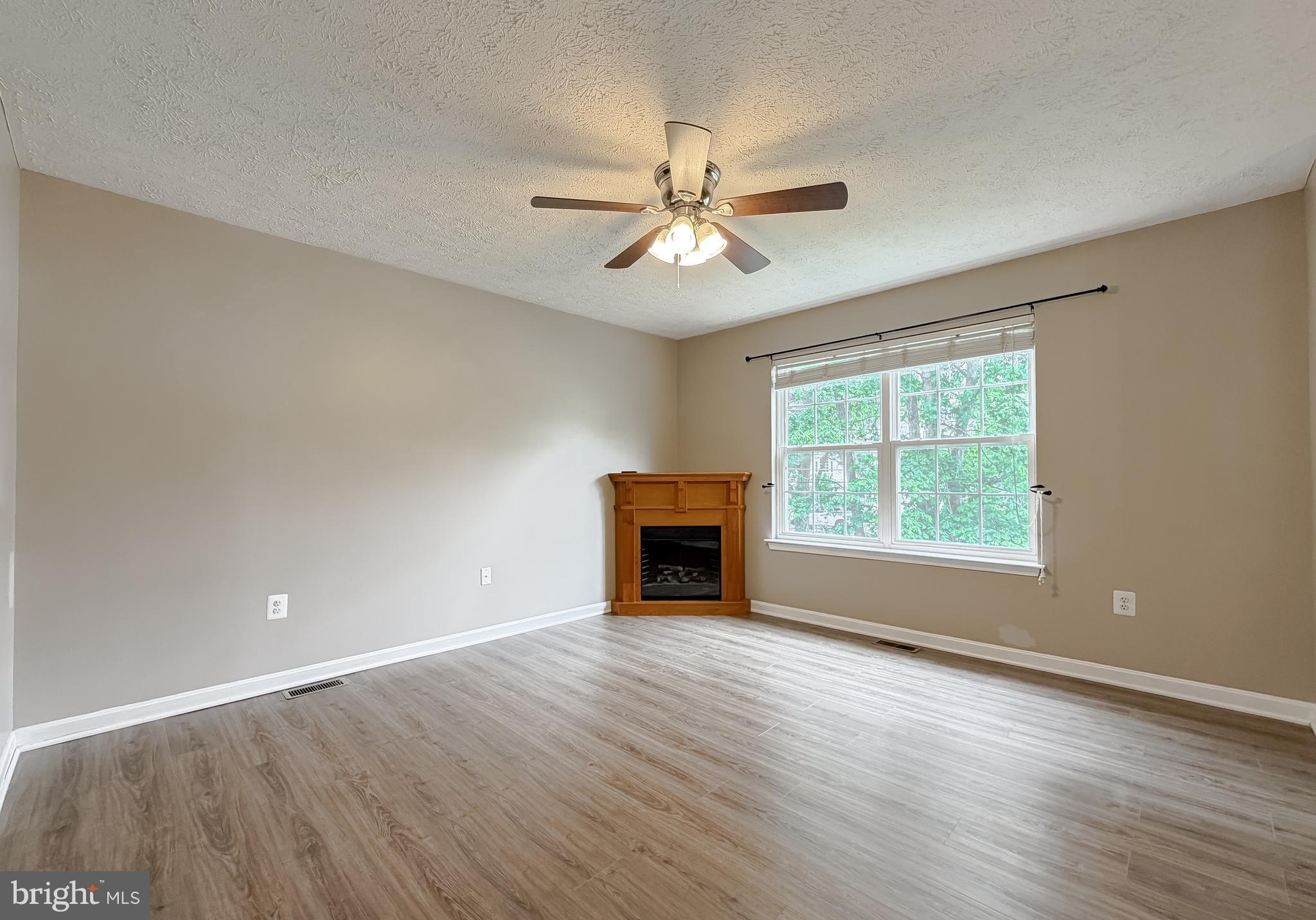 23801 McIntosh Road Hollywood, MD 20636 - Photo 9 of 35 an empty room with wooden floor chandelier fan and windows