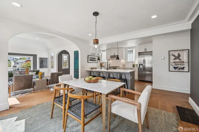 a kitchen with stainless steel appliances a dining table chairs stove and cabinets