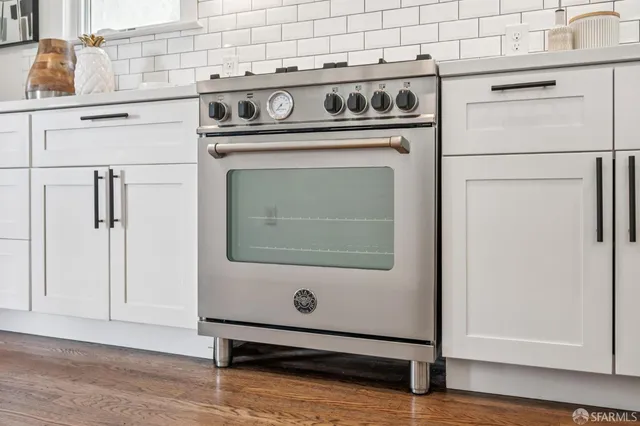 a kitchen with stainless steel appliances sink a refrigerator and white cabinets