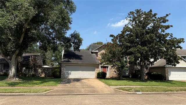 a front view of a house with a garden and tree