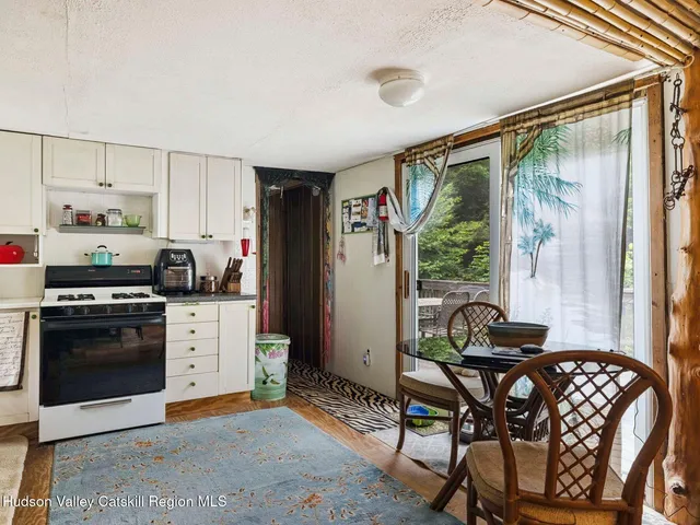 a kitchen with stainless steel appliances granite countertop a stove a refrigerator a dining table and chairs with the wooden floor