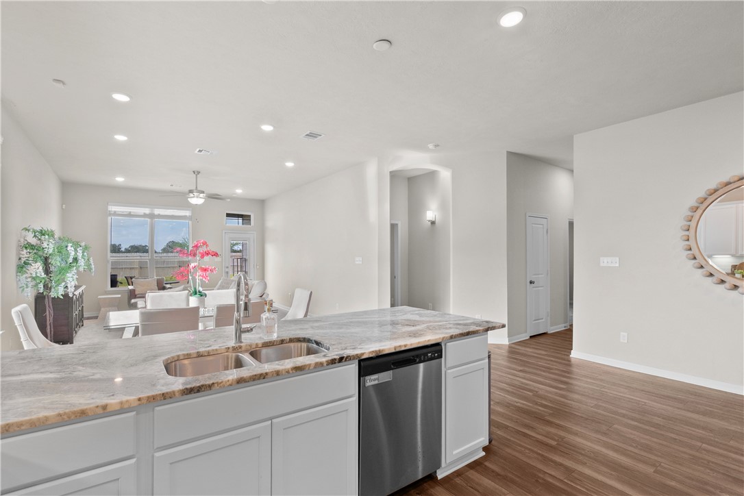 1932 Viva Road Bryan, TX 77807 - Photo 38 of 38 Kitchen featuring open floor plan, dishwasher, a ceiling fan, dark wood finished floors, and light stone countertops