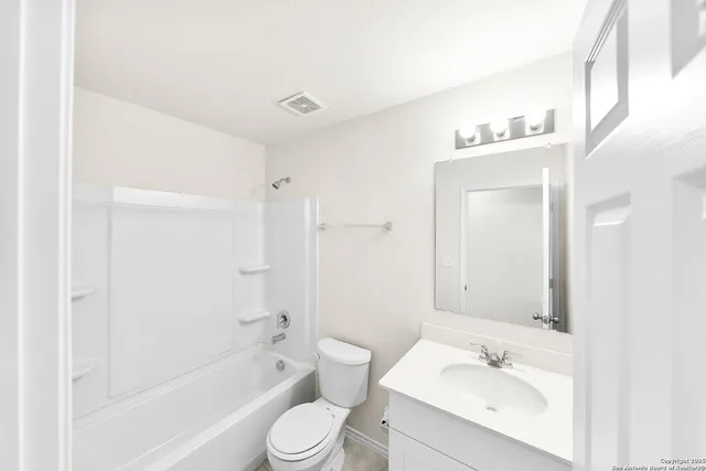 a bathroom with a bathtub shower sink mirror vanity and a toilet