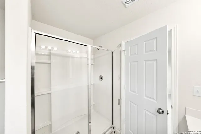 a bathroom with a glass shower door and a shower