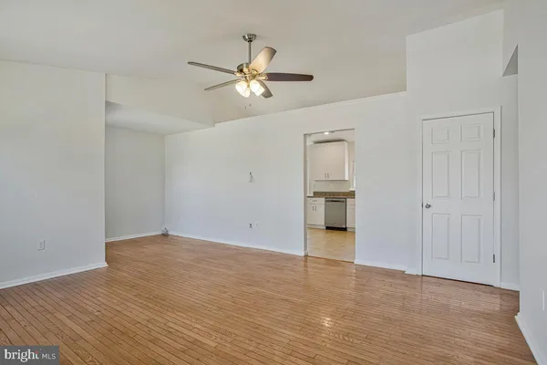 a view of empty room with wooden floor and ceiling fan