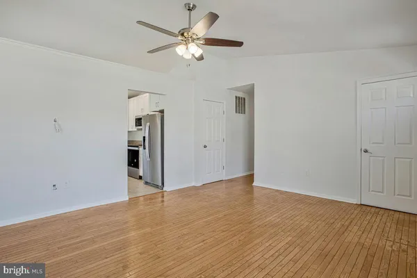 an empty room with wooden floor and ceiling fan